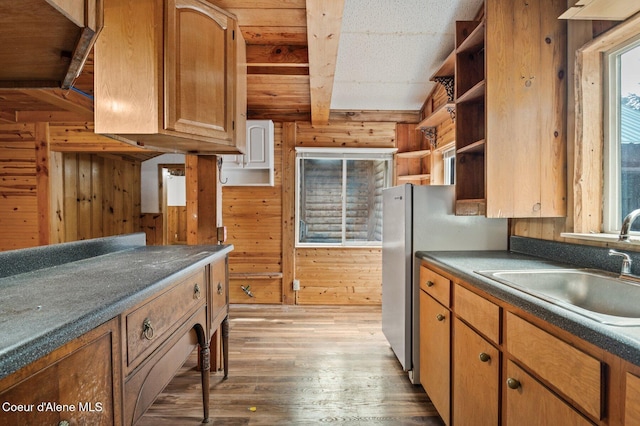kitchen featuring wood walls, open shelves, a sink, dark countertops, and wood finished floors
