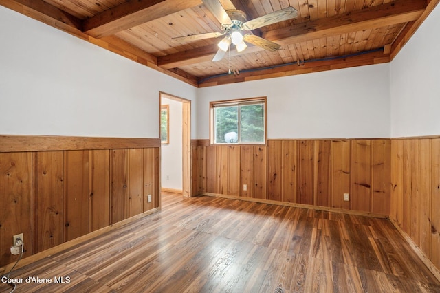 empty room with a wainscoted wall, beamed ceiling, wood finished floors, and wood ceiling