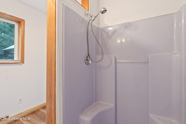 full bath featuring baseboards, wood finished floors, and walk in shower