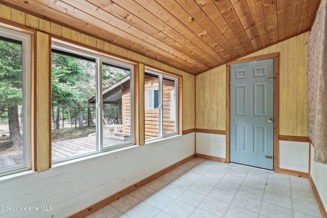 unfurnished room with wooden ceiling, wood walls, light floors, lofted ceiling, and baseboards