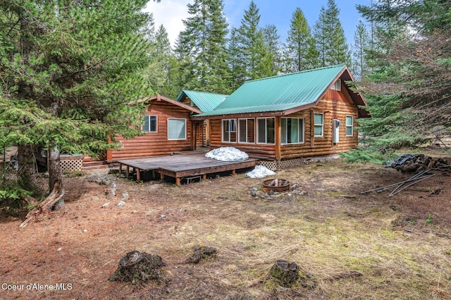 back of property with an outdoor fire pit, log exterior, a deck, and metal roof