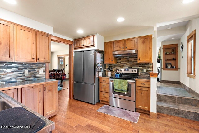 118 E Lincoln Ave, Harrison, ID 83833 - kitchen with tasteful backsplash, light wood-style floors, under cabinet range hood, and appliances with stainless steel finishes