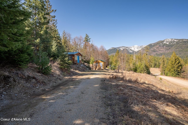 view of road featuring a wooded view, a mountain view, and driveway