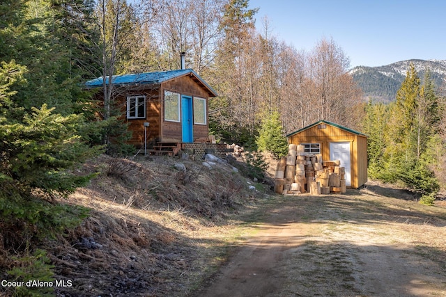 view of outdoor structure with entry steps, a wooded view, a mountain view, and an outdoor structure