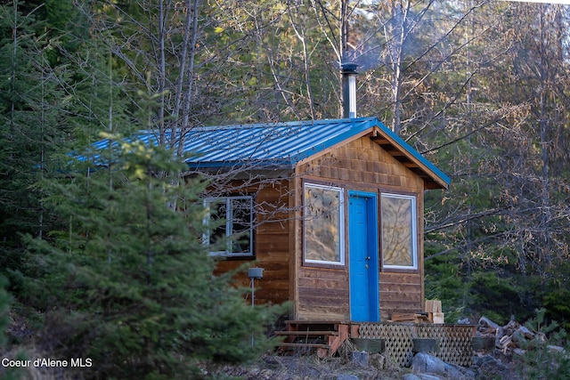 view of outbuilding featuring a view of trees and entry steps