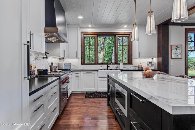 2623 E Old Barn Ct, Harrison, ID 83833 - kitchen with white cabinetry, tasteful backsplash, stainless steel appliances, dark wood-style floors, and wall chimney range hood
