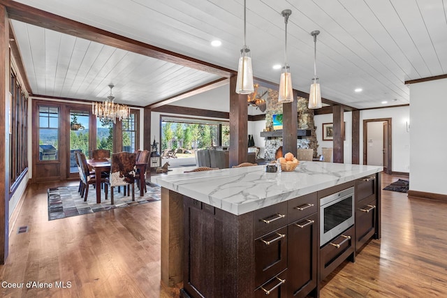 2623 E Old Barn Ct, Harrison, ID 83833 - kitchen with stainless steel microwave, wood finished floors, decorative light fixtures, vaulted ceiling with beams, and an inviting chandelier