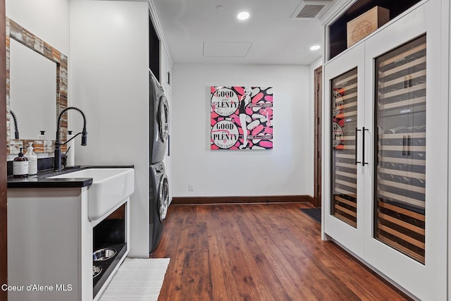 2623 E Old Barn Ct, Harrison, ID 83833 - washroom featuring dark wood-style flooring, baseboards, stacked washing maching and dryer, a sink, and visible vents