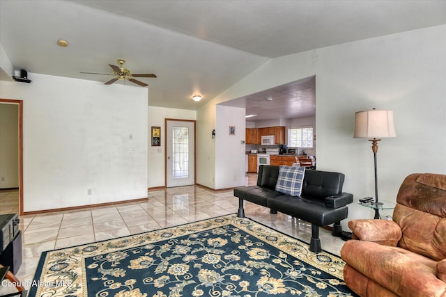 living area with a ceiling fan, light tile patterned floors, baseboards, and lofted ceiling