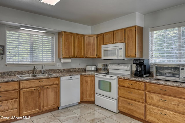 kitchen with a sink, dark countertops, plenty of natural light, and white appliances