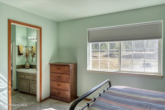bedroom featuring baseboards, ensuite bath, and light tile patterned floors