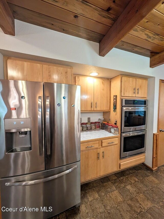 kitchen with beam ceiling, stone finish floor, light countertops, wood ceiling, and appliances with stainless steel finishes