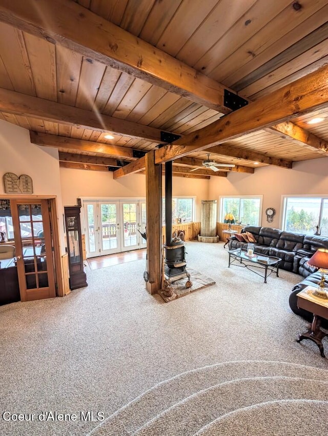 living area with french doors, beamed ceiling, carpet, and a wood stove