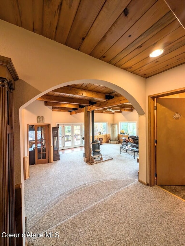 interior space featuring french doors, carpet flooring, arched walkways, and wooden ceiling