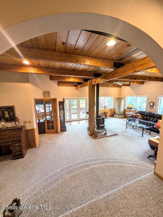 living room with beam ceiling, wooden ceiling, french doors, arched walkways, and carpet