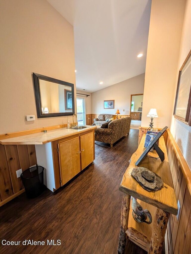 kitchen with lofted ceiling, open floor plan, dark wood-type flooring, light countertops, and a sink