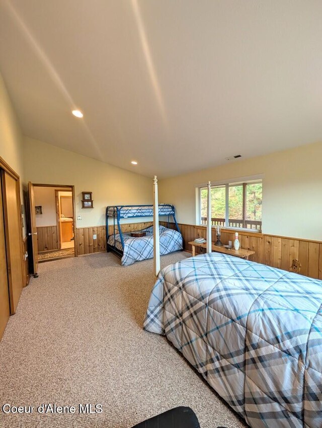 bedroom with carpet flooring, wooden walls, and wainscoting