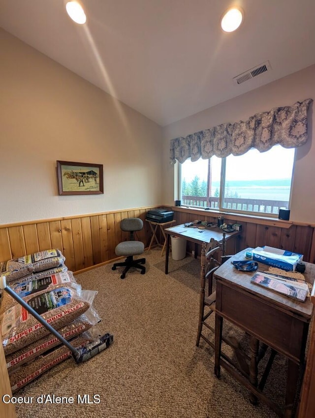 carpeted home office with wainscoting, lofted ceiling, wooden walls, and visible vents