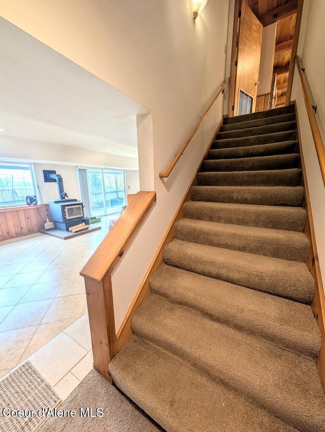 staircase with tile patterned flooring and a wood stove