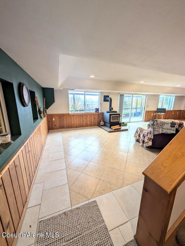interior space with wooden walls, light tile patterned flooring, recessed lighting, and a wood stove