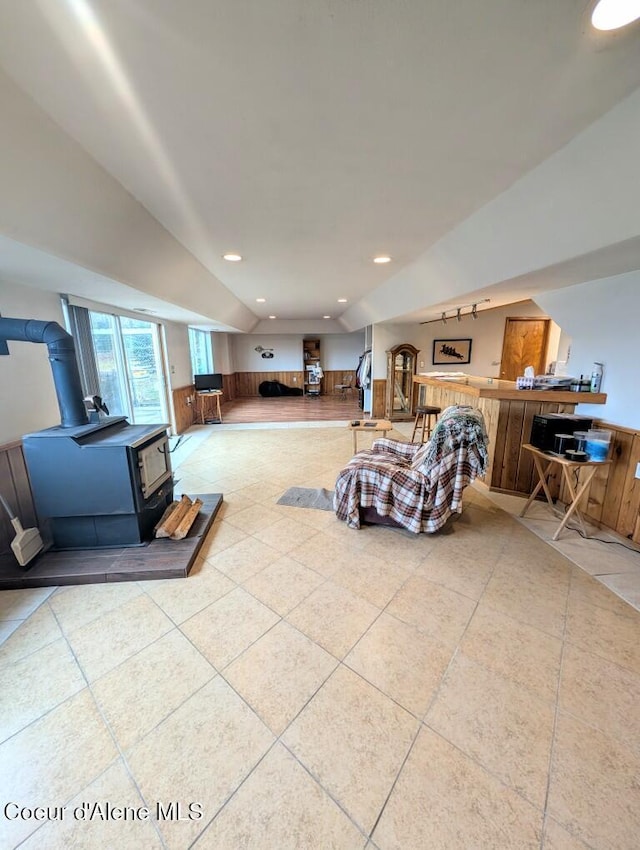 tiled living room with recessed lighting, a wood stove, wainscoting, and wood walls