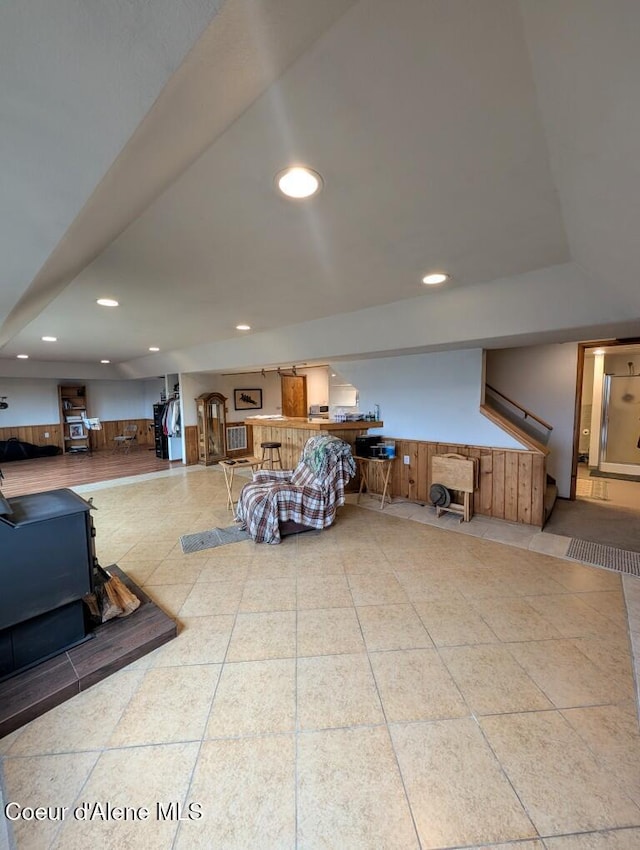 tiled living area with recessed lighting, a wood stove, and a wainscoted wall