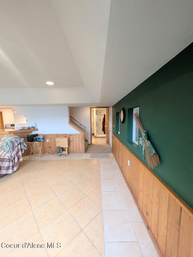 interior space featuring wooden walls, stairs, wainscoting, and light tile patterned floors