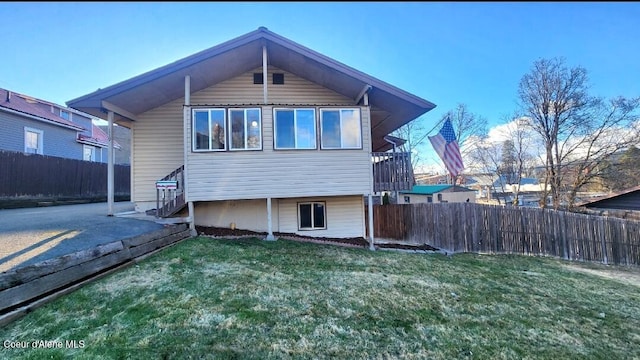 back of property with fence and a lawn