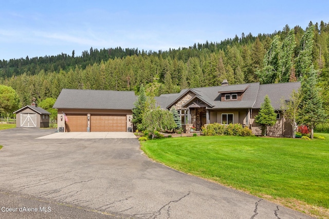 1990 S Gateway Ranch Rd, Coeur Dalene, ID 83814 - rustic home with aphalt driveway, a view of trees, a front yard, stone siding, and a chimney