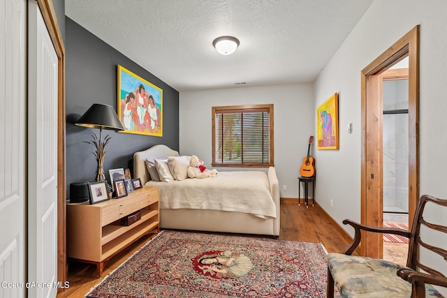 1990 S Gateway Ranch Rd, Coeur Dalene, ID 83814 - bedroom with ensuite bathroom, a textured ceiling, visible vents, wood finished floors, and baseboards