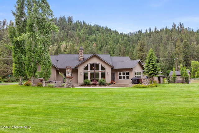 1990 S Gateway Ranch Rd, Coeur Dalene, ID 83814 - rear view of property featuring a yard, a view of trees, and a chimney