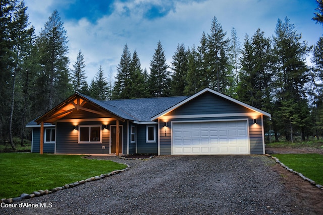 ranch-style home featuring gravel driveway, a front yard, a shingled roof, and an attached garage