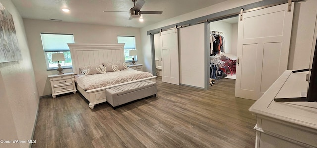 bedroom with a closet, a walk in closet, a barn door, and wood finished floors