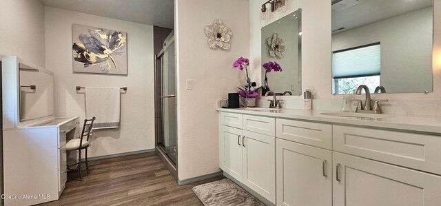 bathroom with double vanity, a sink, a stall shower, and wood finished floors