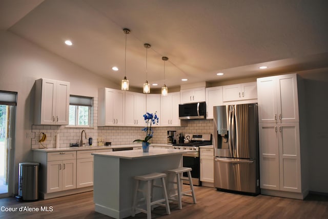 kitchen featuring dark wood finished floors, light countertops, vaulted ceiling, and appliances with stainless steel finishes