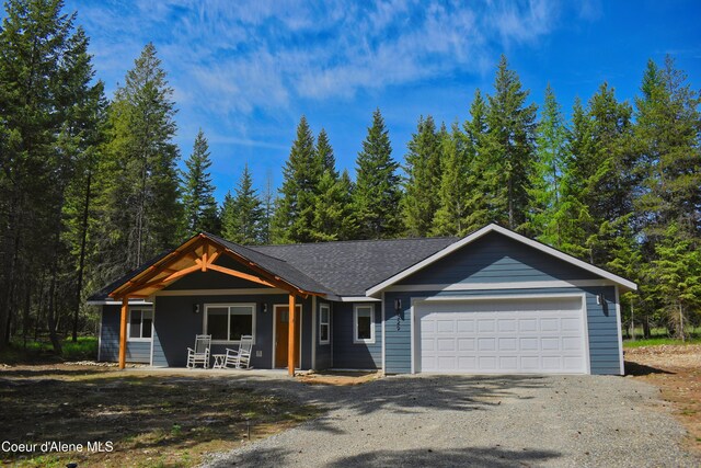 view of front of home featuring aphalt driveway, a garage, and a porch