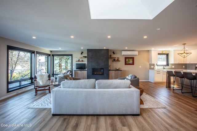 475 Campbell Point Rd, Laclede, ID 83841 - living room with an AC wall unit, healthy amount of natural light, wood finished floors, a tiled fireplace, and recessed lighting