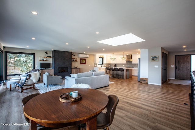 475 Campbell Point Rd, Laclede, ID 83841 - dining area with a wall unit AC, a skylight, recessed lighting, wood finished floors, and a fireplace
