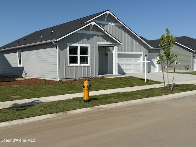 5181 E Aquila Ave, Post Falls, ID 83854 - view of front of home with board and batten siding, driveway, a front lawn, an attached garage, and a shingled roof