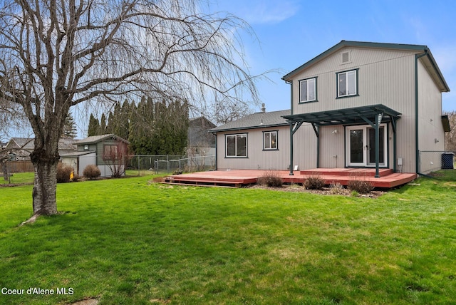 back of house featuring fence, a wooden deck, a lawn, and a pergola