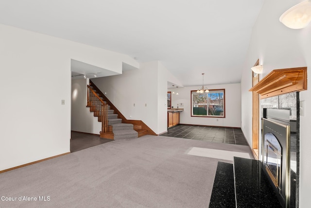 unfurnished living room featuring carpet, stairway, lofted ceiling, a notable chandelier, and baseboards