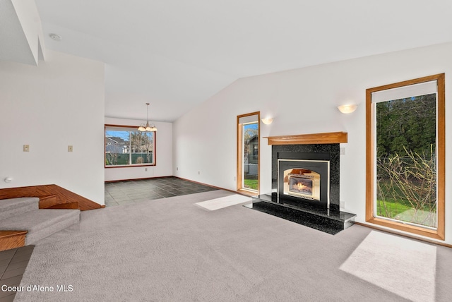 unfurnished living room with baseboards, a chandelier, carpet, vaulted ceiling, and a premium fireplace