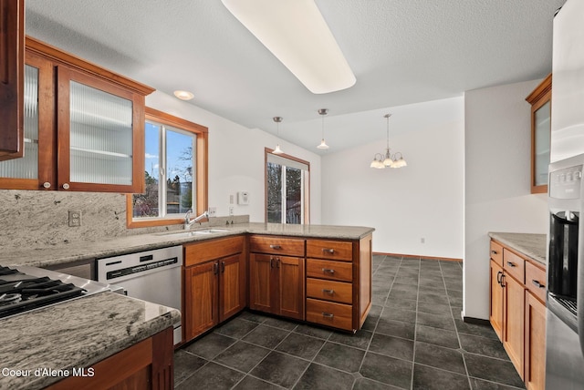 kitchen featuring an inviting chandelier, a peninsula, decorative light fixtures, dishwasher, and a sink