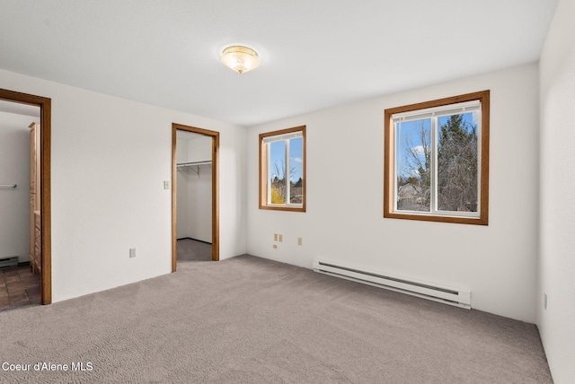 unfurnished bedroom featuring a spacious closet, carpet, and a baseboard heating unit