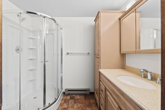 full bathroom with a shower stall, vanity, baseboard heating, and stone finish flooring
