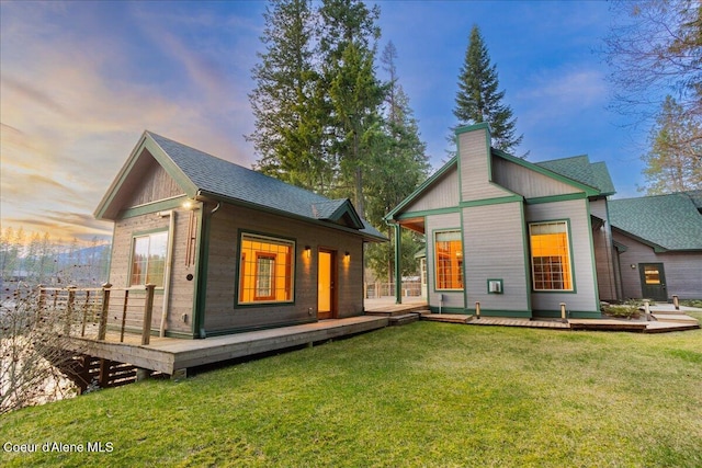 back of property with a yard, a wooden deck, and an outbuilding