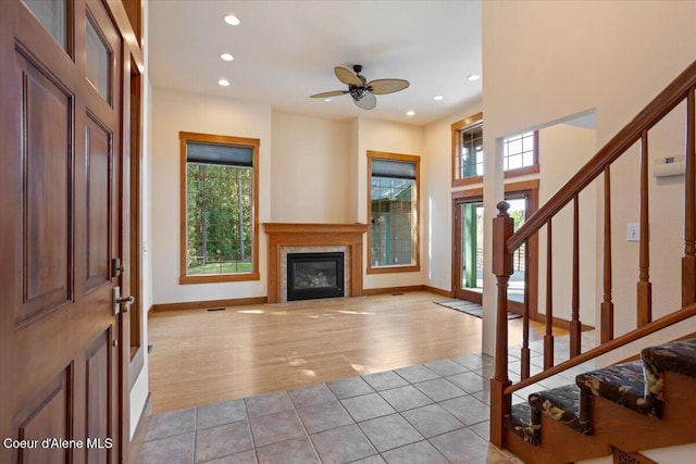 entryway with a glass covered fireplace, recessed lighting, light tile patterned flooring, stairs, and ceiling fan