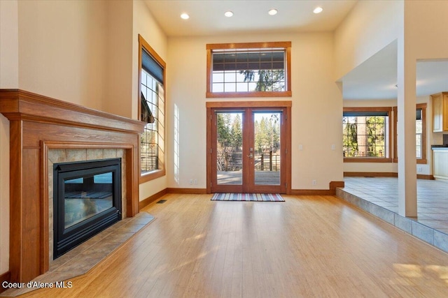 entryway featuring visible vents, baseboards, a towering ceiling, and wood finished floors