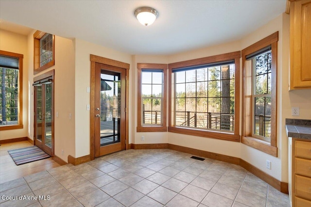 doorway featuring light tile patterned flooring, baseboards, and visible vents