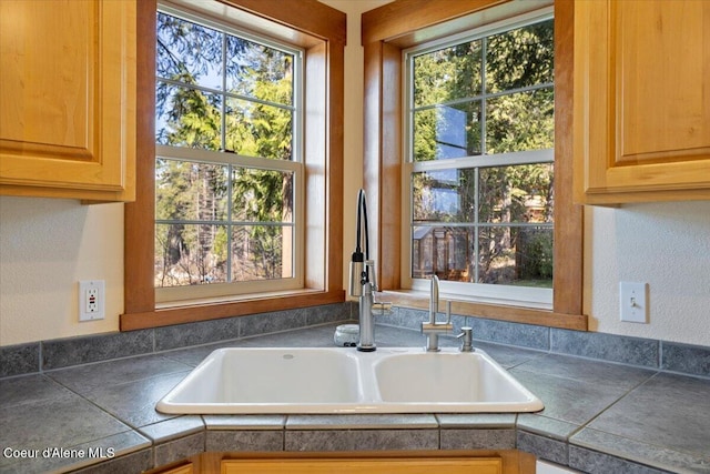 room details with a sink, tile counters, a textured wall, and dishwasher
